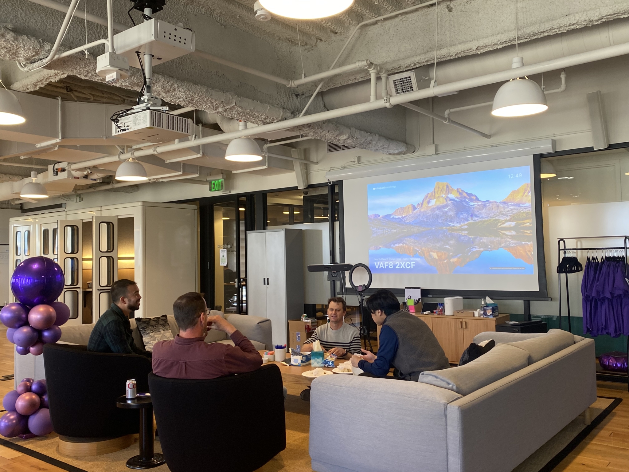 Dialpad employees at the WeWork office in San Francisco sit around a large coffee table in a lounge space.
