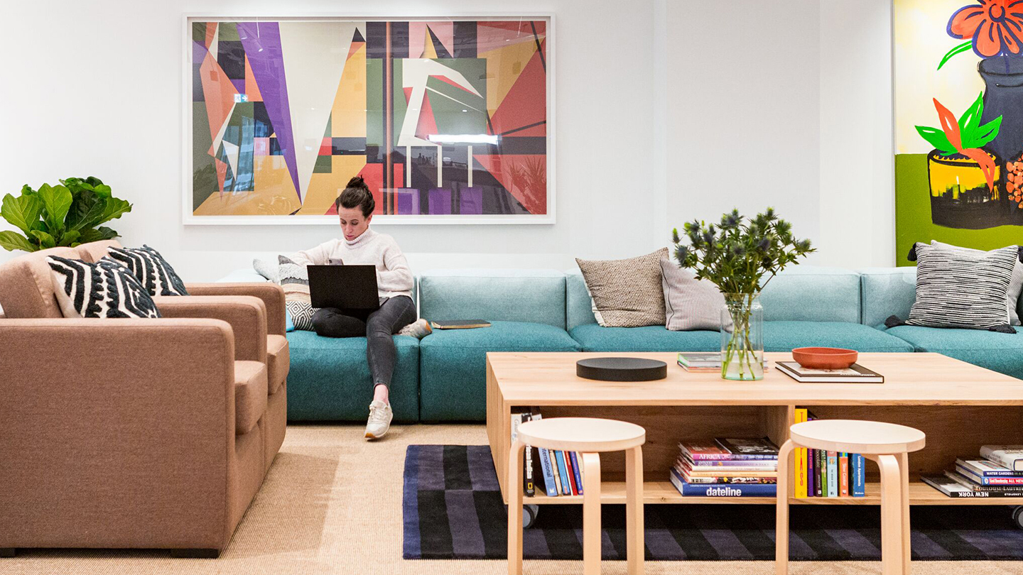 img src="wework30churchill.jpg" alt="woman working on laptop sitting on couch in coworking space">