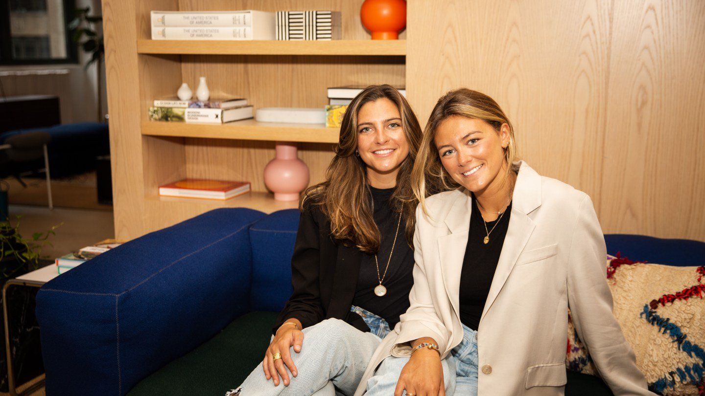 Brooke and Katherine Naylor sitting on a couch in front of book shelf
