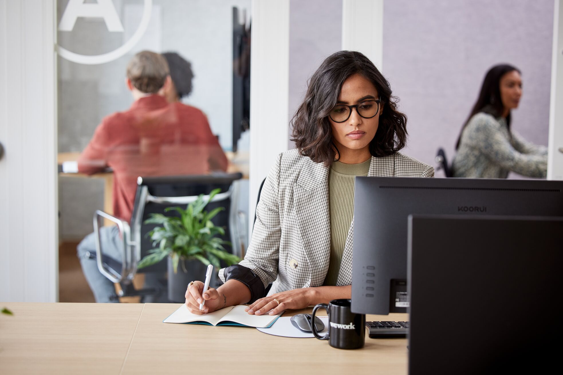 Woman looking at a screen and taking notes.