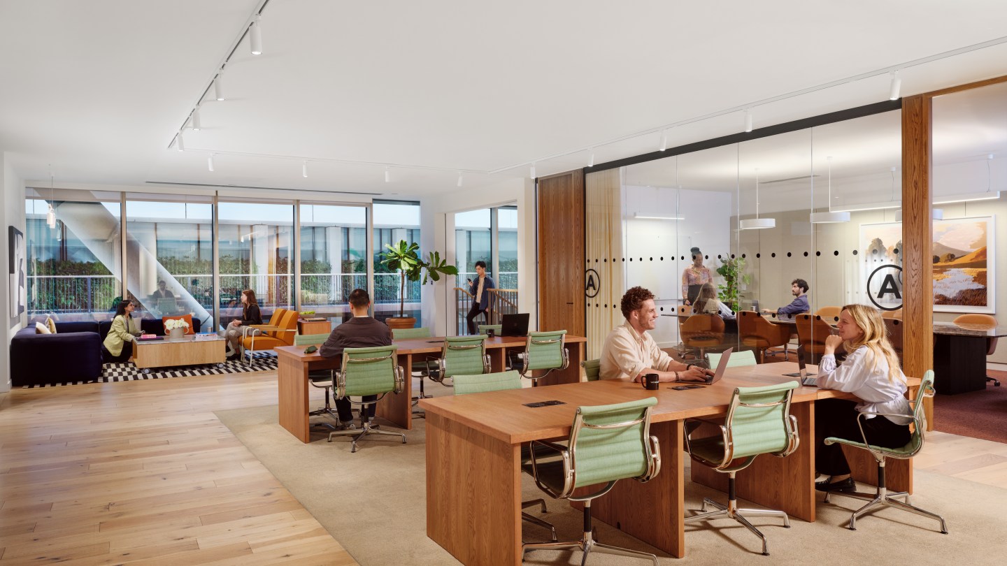 people in working and socializing in meeting rooms, lounge areas, and a few desks