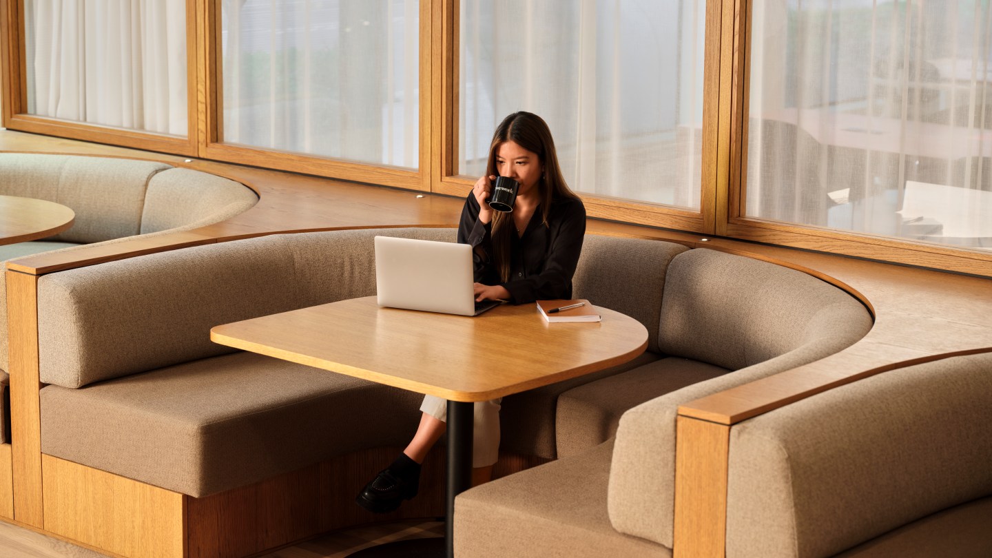 WeWork member sitting at a table with laptop and coffee