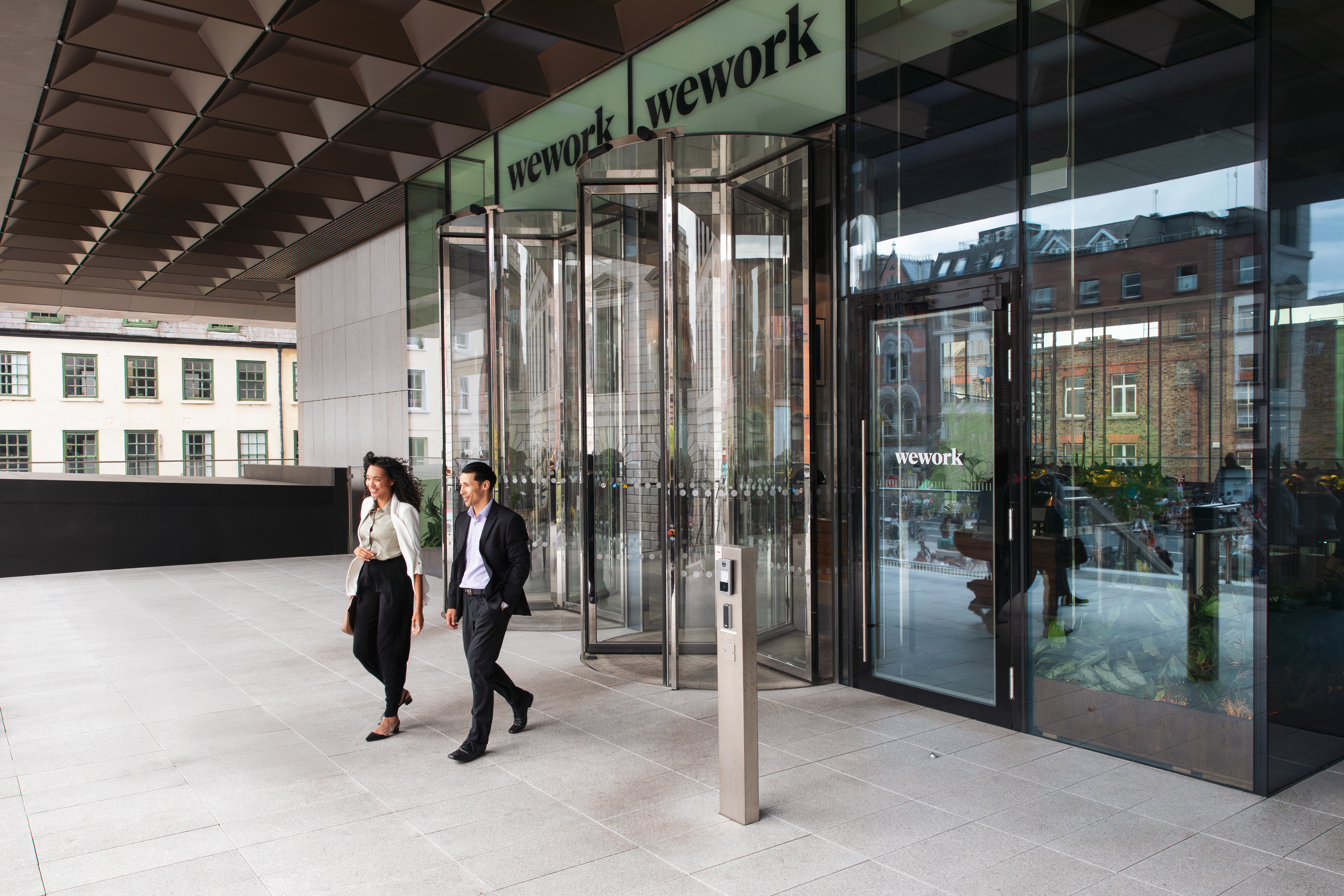 two smartly dressed people leaving a WeWork building