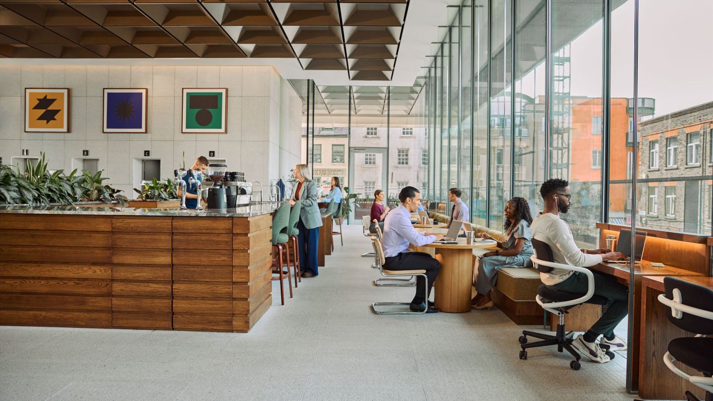 People working or chatting in various seating areas in an open coworking space.