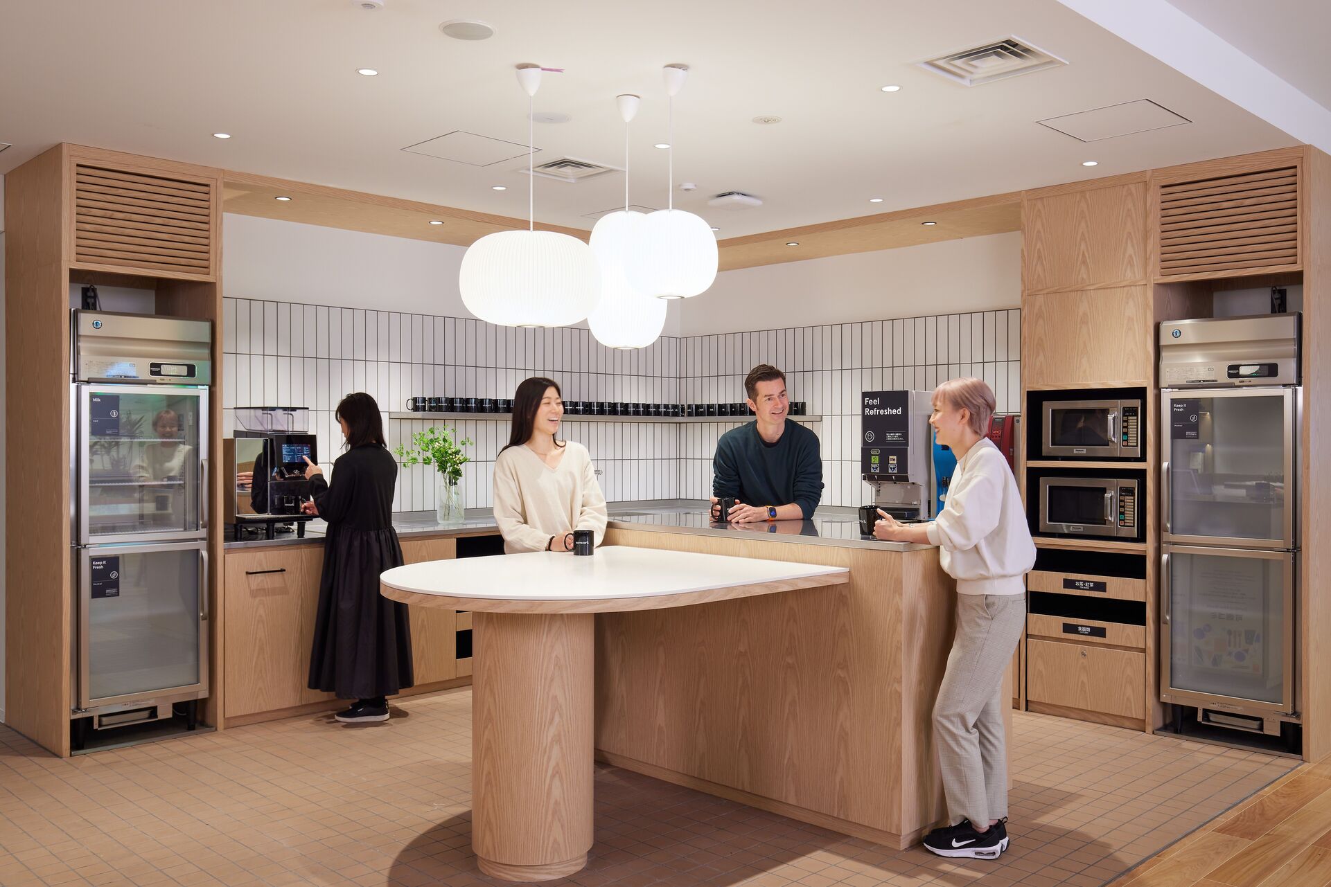 People chatting around the table in workspace kitchen area.