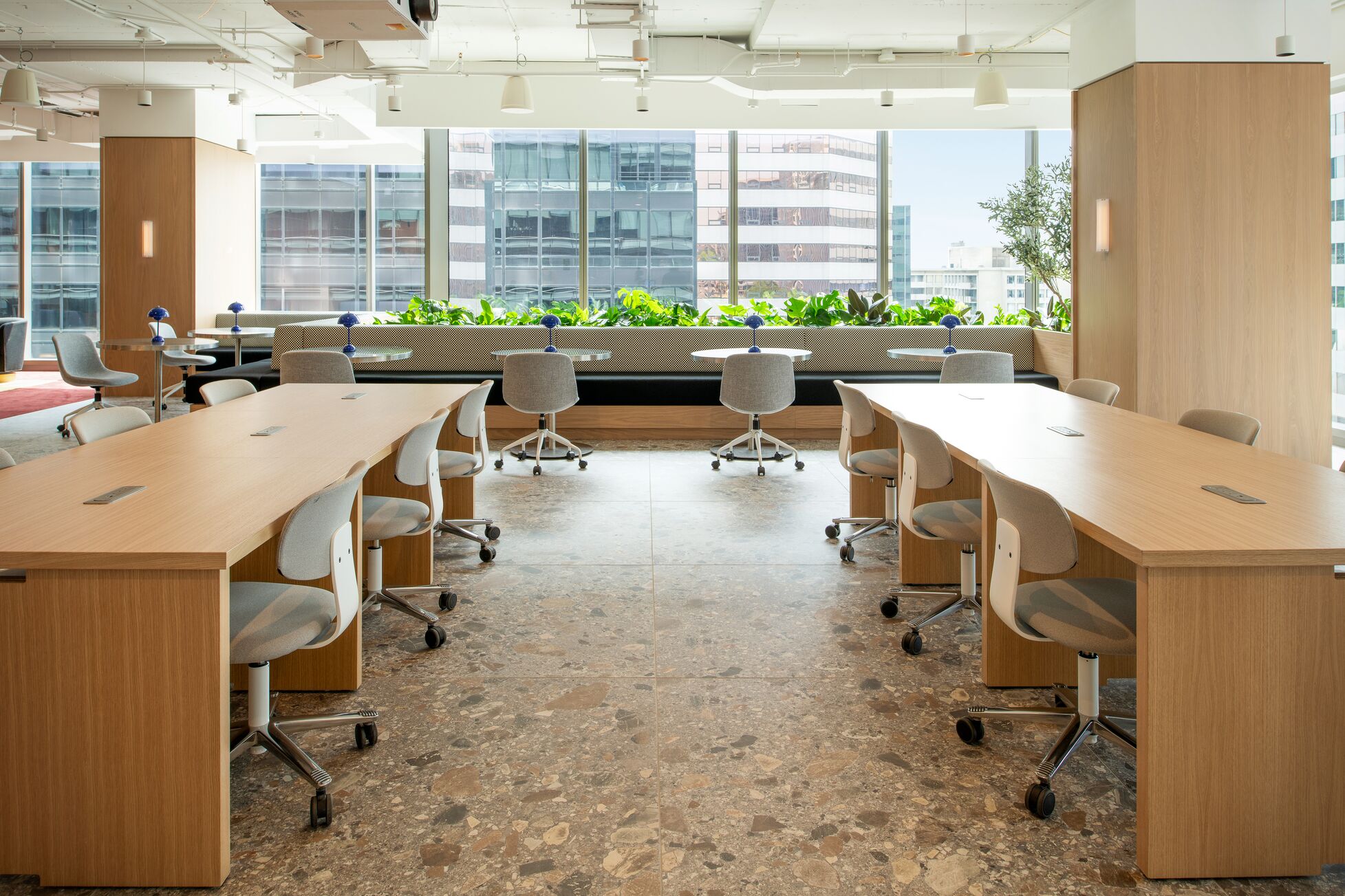 A well-lit office space with desks on both sides and floor-to-ceiling window in the front.