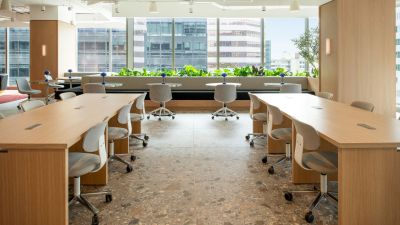 A well-lit office space with desks on both sides and floor-to-ceiling window in the front.