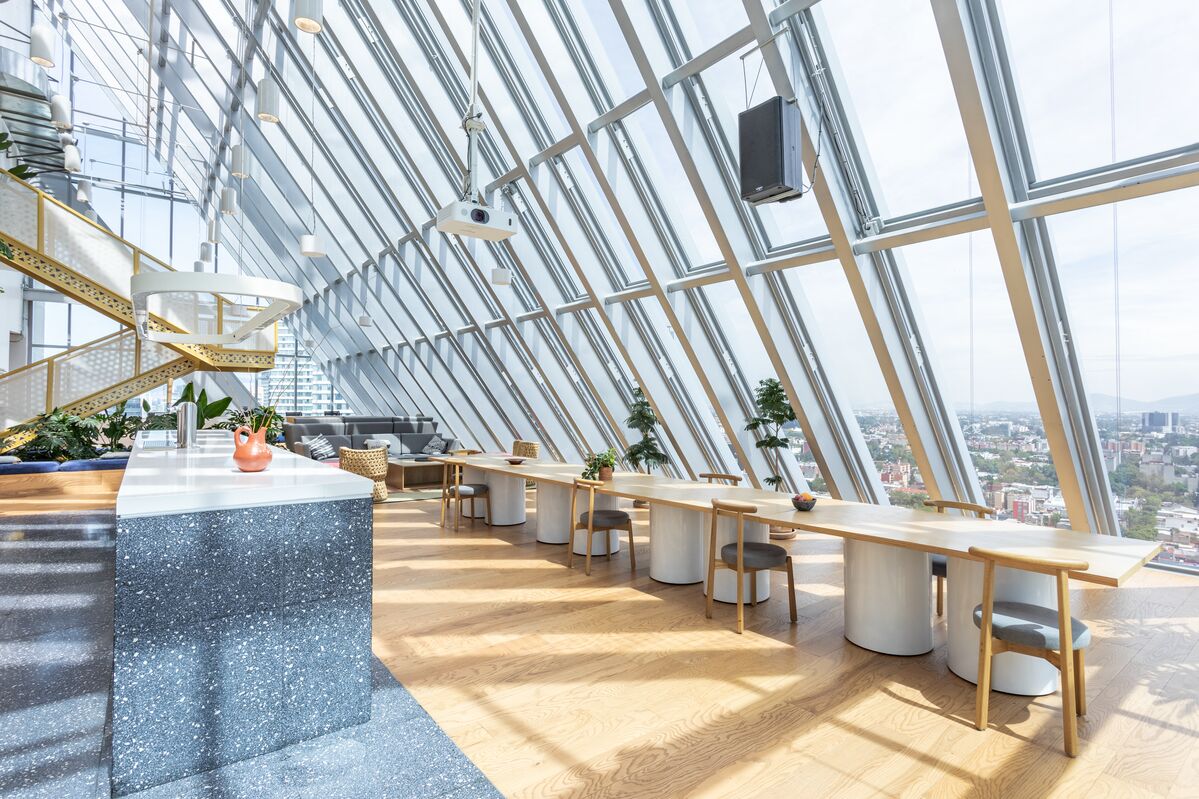 Seating area with chair and tables overlooking the view out floor-to-ceiling windows.