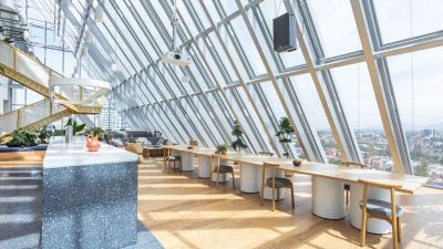 Seating area with chair and tables overlooking the view out floor-to-ceiling windows.