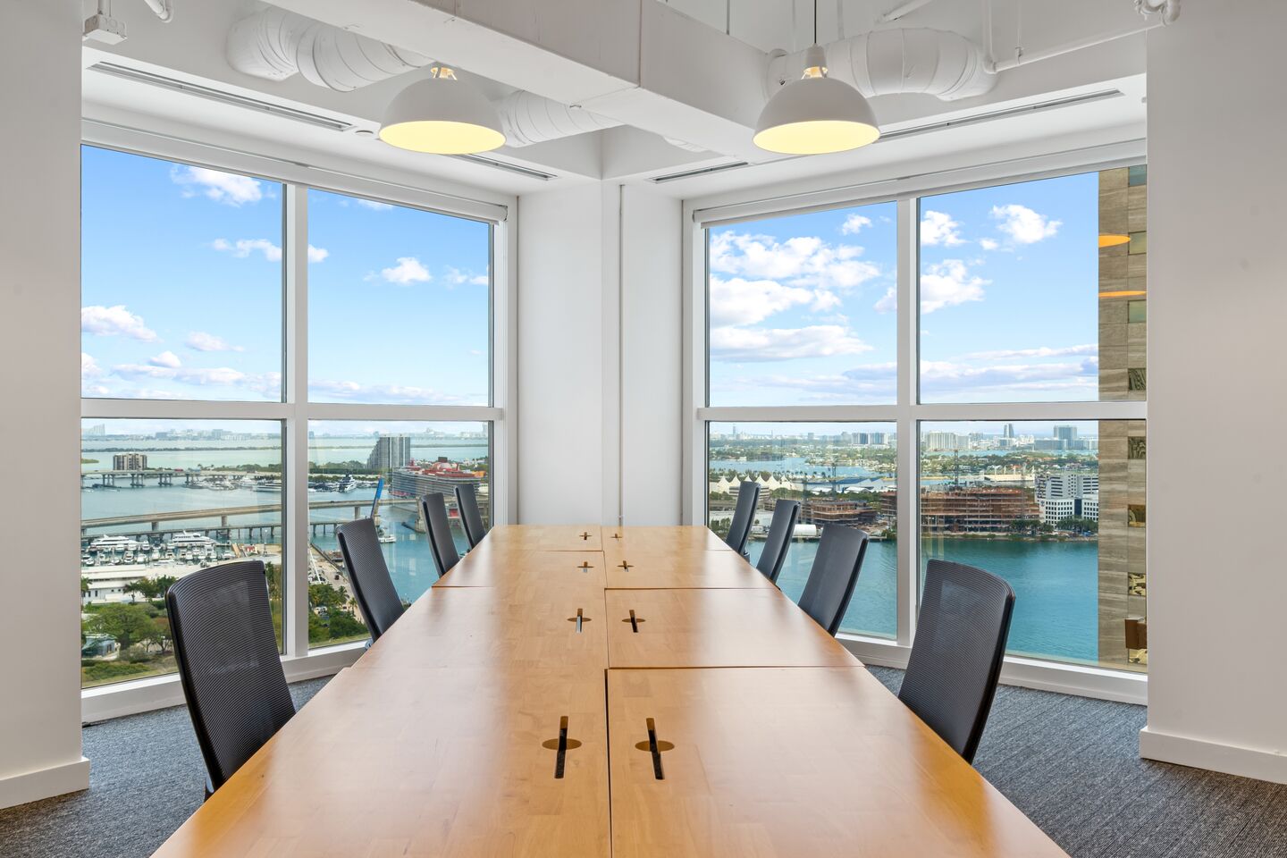 A conference table with chairs; behind them, large windows showing the cityscape.