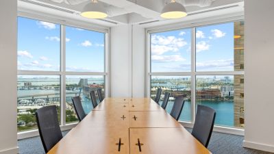 A conference table with chairs; behind them, large windows showing the cityscape.