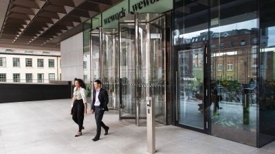 Two people walking out of a WeWork building.